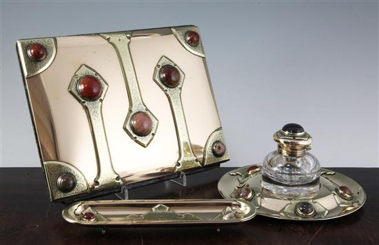 An early 20th century Arts & Crafts Scottish cabochon hardstone mounted brass and copper desk set, blotter 11in.